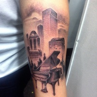 Vintage photo like black and white forearm tattoo of city sights and piano