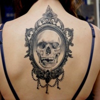 Vintage style black and white human skull portrait tattoo on back stylized with night butterfly