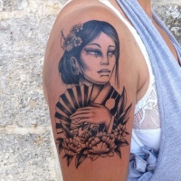 Tatuaje negro blanco en el brazo,
geisha carismática con abanico y flores