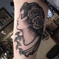 Vintage style black ink biceps tattoo of woman with flowers