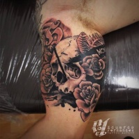 Vintage style colored biceps tattoo of human skull with flowers and lettering