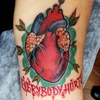 Vintage style colored biceps tattoo of human heart with arrows and lettering