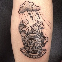 Tatuaje en el brazo,
barco pequeño en taza de té, estilo vintage