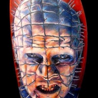 Tatuaje en la pierna, monstruo con clavos clavados en la cara