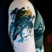 Tatuaggio astratto sul deltoide l'uccello nero con la becca gialla