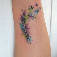Tatuaje en el antebrazo,
pluma multicolor con aves diminutos