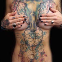 Tatuaje en el pecho y estómago, cráneo de toro y atrapasueños multicolores