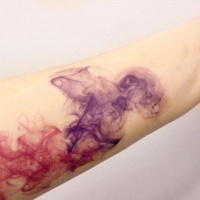 Watercolor like multicolored abstract tattoo on arm