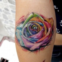 Watercolor like multicolored little rose tattoo on arm