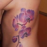Aquarell Tattoo mit schönen Orchideen an Rippen