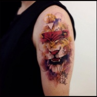 Watercolor style colored shoulder tattoo of lion with lettering