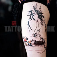 Watercolor style colored thigh tattoo of swimming birds and tree branches