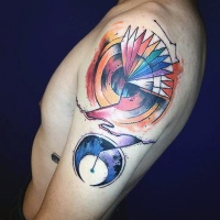 Watercolor style colored upper arm tattoo of circle shaped ornament and moon