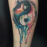 Watercolor style medium size Yin Yang symbol tattoo on forearm