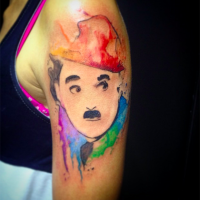 Watercolor style nice looking shoulder tattoo of Charlie Chaplin