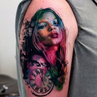 Watercolor style painted multicolored woman portrait tattoo on shoulder with old clock