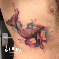 Wal mit weit geöffnetem Kiefer Tattoo auf der Seite mit farbigen Aquarellfarbentropfen