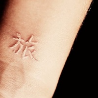Weiße Tinte chinesische Hieroglyphe Tattoo am Handgelenk
