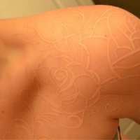 Tatuaje en el hombro, rosas encantadas de tinta blanca