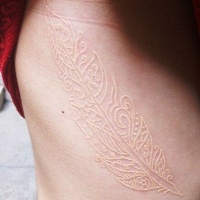 White ink stylized feather tattoo on ribs