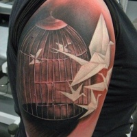 White origami birds flying out of cage  tattoo on shoulder