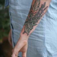 Tattoo mit Wildblumen und Feder am Unterarm