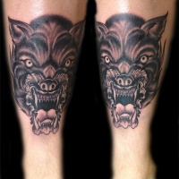 Tatuaggio spaventoso sulla gamba la faccia del lupo con la bocca spalancata