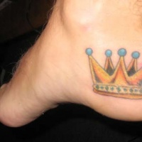 Yellow crown tattoo on foot