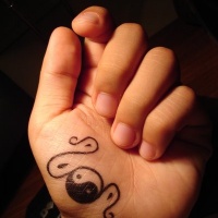 Tatuaggio piccolo sulla mano il disegno nero in stile Yin-Yang