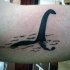 Tatuaje en el brazo, monstruo del lago Ness en el agua, tinta negra