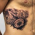 Tatuaje en las costillas, mapa del mundo con compás y avion de papel