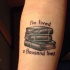 Tatuaje de  libros y cita en el antebrazo