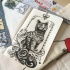 Black-and-white imperial cat in floral frame tattoo design