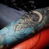Blue flower and black skull tattoo on arm
