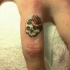 particolre piccolo cranio femminile con fiore tatuaggio su indice