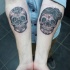 Tatuaje en los antebrazos, calaveras sonrientes de azucar grises