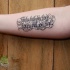 scrittura particolare nero con tanti riccioli tatuaggio su braccio