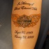Tatuaje en el antebrazo, logo de harley davidson con alas naranjas