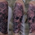 Tatuaggio con grandi teschi e rose sulla spalla