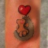 Tatuaje de erizo con globo corazón en la muñeca