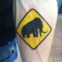 Tatuaje en el antebrazo, signo de mamut, colores amarillo y negro