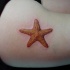 realistica arancione stella marina tatuaggio su coscia di ragazza