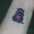 Tatuaje en la muñeca,
hipopótamo pequeño de dibujos animados con corazón rojo en patas