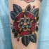 Tatuaje en el brazo,
flor roja tradicional con ojas verdes oscuros