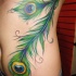 Tatuaje en el costado, plumas de pavo real maravillosas