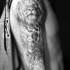 Tatuaje negro blanco en el brazo, ángel con león y inscripción
