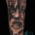 Tatuaje en el brazo,
ruinas antiguas con silueta de cara de hombre anciano