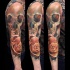 Akkurater naturgetreuer farbiger menschlicher Schädel Tattoo am Ärmel mit realistischer Rose