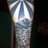 Tatuaje en el antebrazo, olas con montañas y sol, estilo asiático