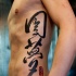 Tatuaje en el costado, inscripción china, tinta negra